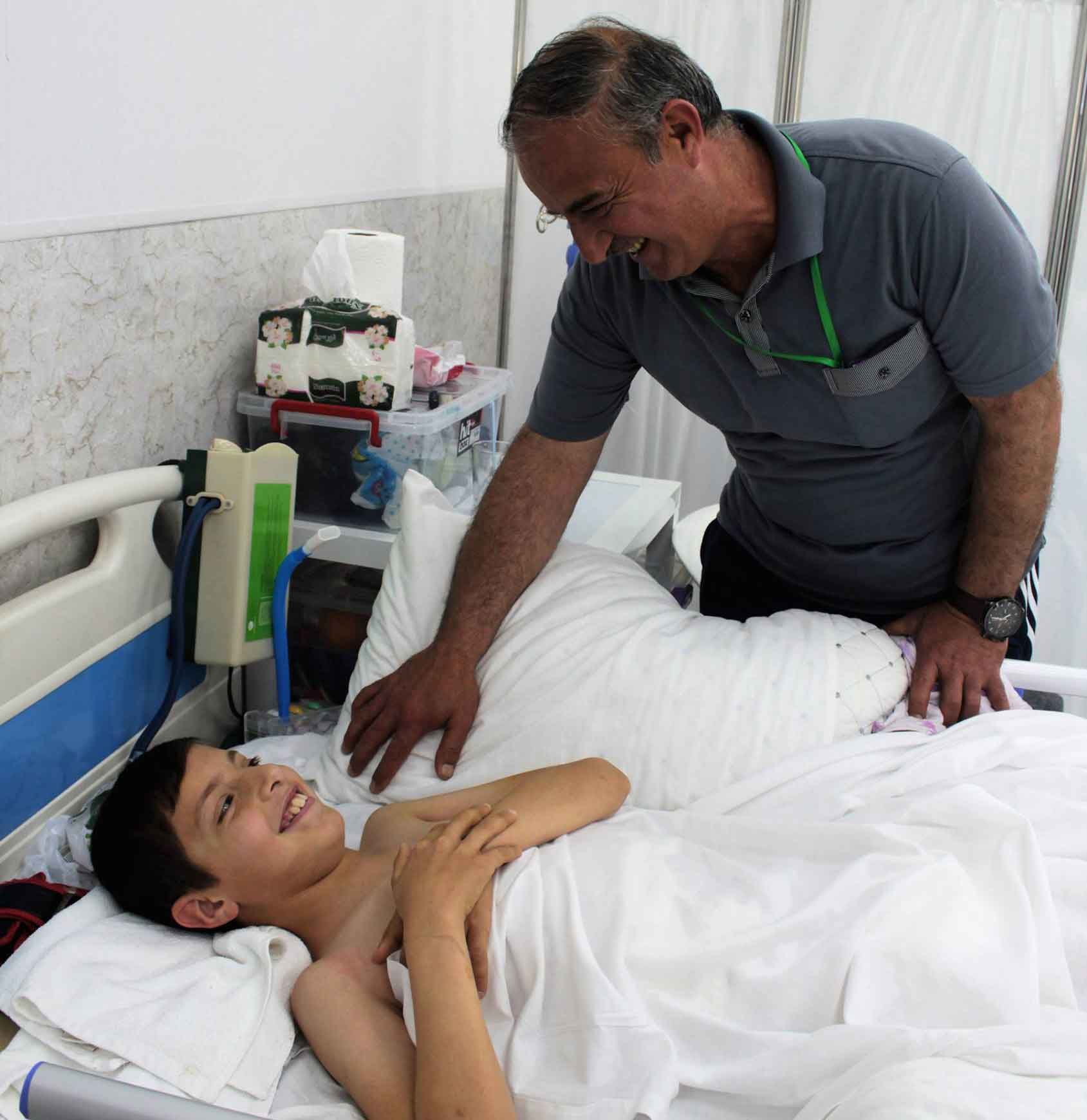 Rayyan (12 years old), war victim, it the Emergency Hospital ward. His father is near him.