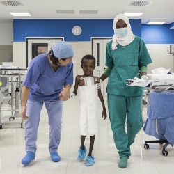 A child walks with a doctor and a nurse in a ward at the Salam Centre for Cardiac Surgery in Khartoum, Sudan